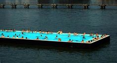 a large swimming pool in the middle of water with people on it and one person standing at the edge