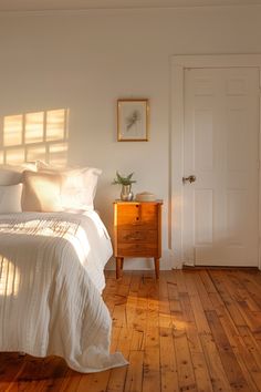 a bedroom with white walls and wooden floors