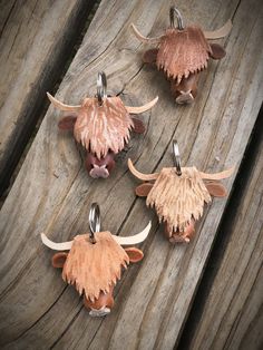 four cow's heads hanging from hooks on a piece of wooden planked surface