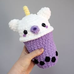 a hand holding a crocheted cup with a bear on it