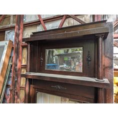 an old wooden fireplace with a mirror on it