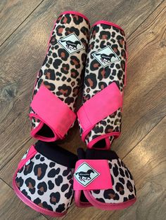 three pairs of pink and black leopard print shoes on wood flooring, with one pair in the middle