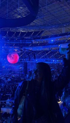 a woman standing in front of a crowd at a concert with bright blue lights on the ceiling