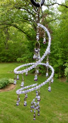 a wind chime hanging from a tree in a yard with grass and trees behind it