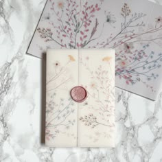 two envelopes with flowers on them and a wax stamp sitting on top of one