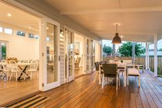 an outdoor dining area with wooden floors and white walls, surrounded by large sliding glass doors