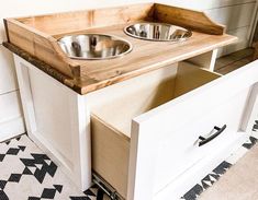 a dog bowl is sitting on top of a wooden cabinet with two bowls in it