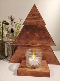 a candle is lit in front of a wooden christmas tree