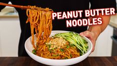 a person holding a bowl of noodles with chopsticks in it and the words peanut butter noodles above them