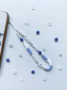 a cell phone with an evil eye beaded necklace on it next to some beads