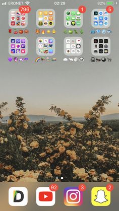 an iphone screen with different icons on it and flowers in the foreground, as well as trees