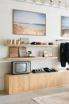 a living room filled with furniture next to a white brick wall and two pictures on the wall