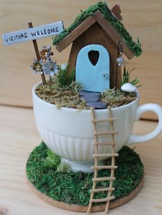 there is a cup with a birdhouse in it and a sign that says vistas welcome