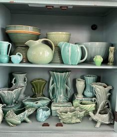 a shelf filled with lots of different colored vases and bowls on top of each other