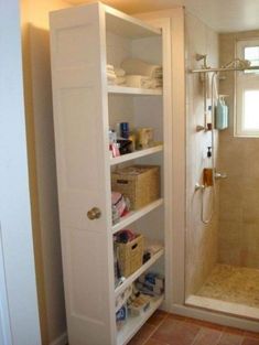 a walk in shower sitting next to a white cabinet filled with bottles and other items