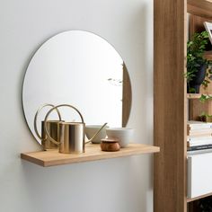 there is a mirror on the wall next to a shelf with pots and pans