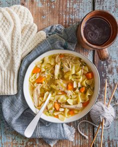 a bowl of chicken noodle soup next to a cup of coffee