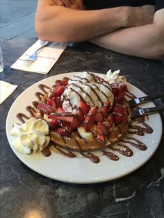 a waffle topped with strawberries and drizzled chocolate on a white plate