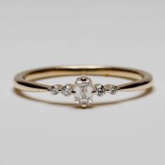 a yellow gold ring with an oval cut diamond and three small round diamonds on the band