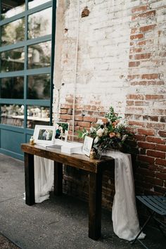 a table with pictures and flowers on it next to a brick wall in front of a door