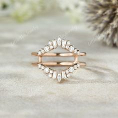 a rose gold ring with white diamonds on it and a pine cone in the background