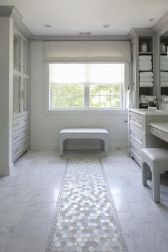 a large bathroom with white marble floors and walls, along with a long window that looks out onto the outdoors