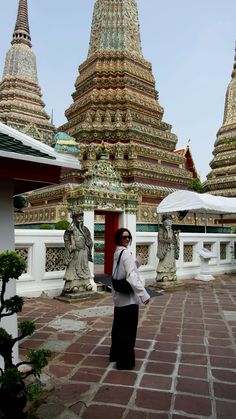 a woman standing in front of an ornate building with many spires and statues around her