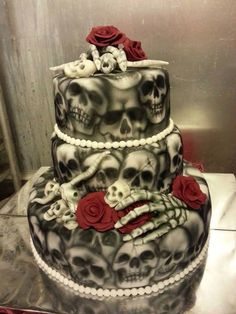 a three tiered cake decorated with skulls and roses