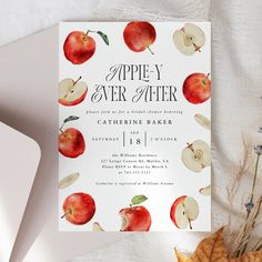 an apple themed wedding card is displayed on a table with autumn leaves and other items