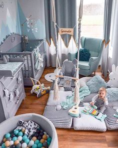 a child's room decorated in blue and grey with toys on the floor, cribs and chairs