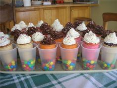 cupcakes in plastic cups with white frosting and sprinkles on them