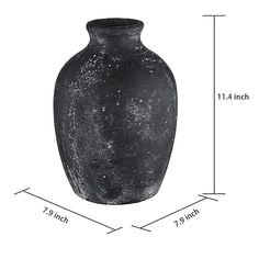 a large black vase sitting on top of a white table next to a measuring line