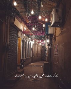 an alley way with lights strung from the ceiling and hanging from the ceiling in arabic writing