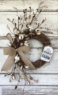 a wreath with cotton and a tag hanging on the side of a door that says rise like a shine