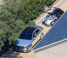 an aerial view of two cars parked on the side of a road next to trees