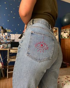 a woman with her back to the camera, wearing jeans that have an eye on them