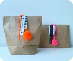 two brown paper bags with pom - poms on them