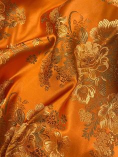 an orange and gold floral print fabric with metallic foil on the bottom half of it