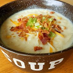 a bowl of soup with bacon, cheese and sour kraut in it on a wooden table