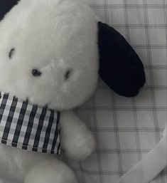 a white stuffed animal with a black and white checkered shirt around it's neck