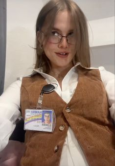 a woman wearing glasses and a brown vest with a badge on it's chest