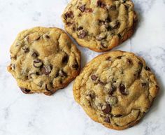 three chocolate chip cookies sitting on top of a counter