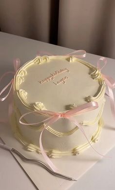 a white cake with pink ribbon and congratulations written on it, sitting on a table