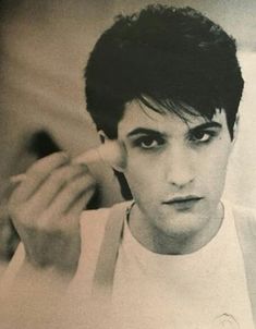 a black and white photo of a young man brushing his hair