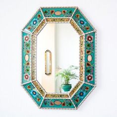 a mirror that is on the wall near a potted plant in front of it