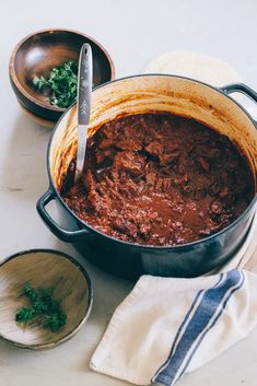 a pot full of chili next to two wooden bowls