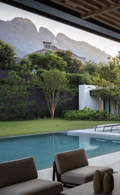 an outdoor living area with couches and chairs next to a swimming pool in front of mountains