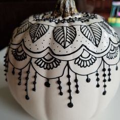 a white pumpkin decorated with black designs on it's side sitting on a table