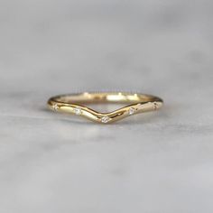 a yellow gold wedding band with three diamonds on the top and bottom, sitting on a marble surface