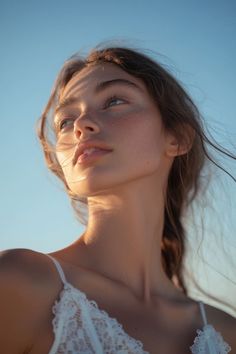 a woman with her eyes closed wearing a white bra and looking up at the sky